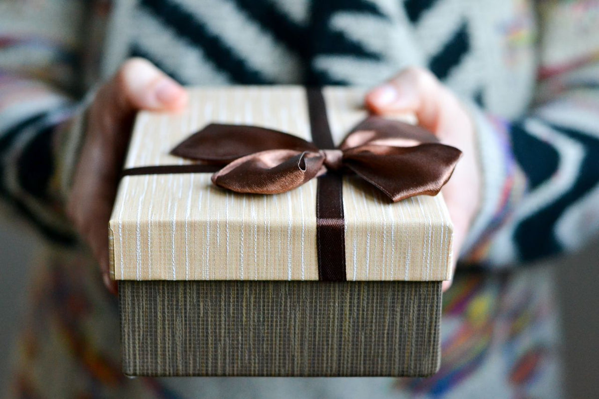 Stylish gift box with brown ribbon held in hands, perfect for holidays and celebrations